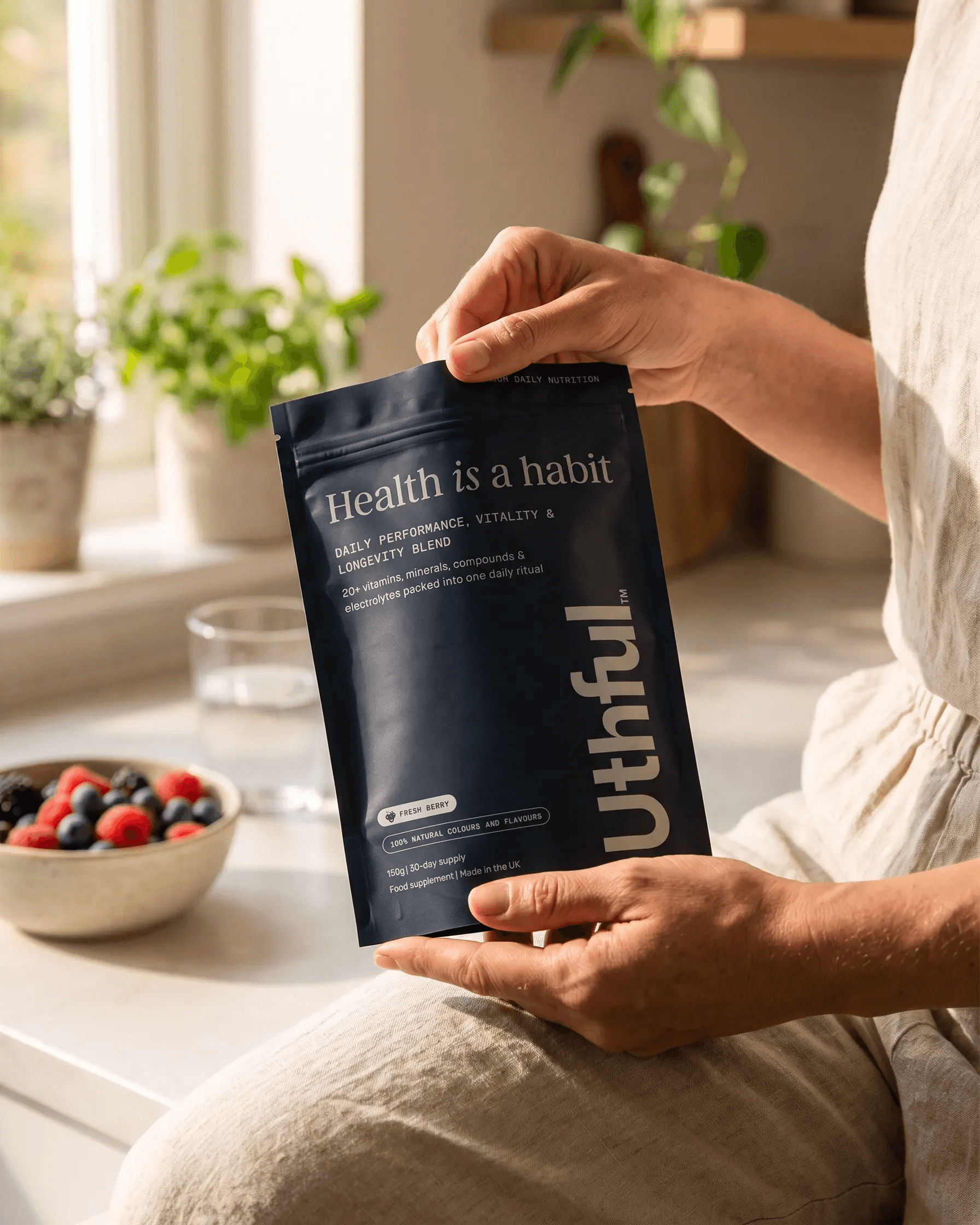 Person holding an Uthful daily nutrition pouch in a bright kitchen