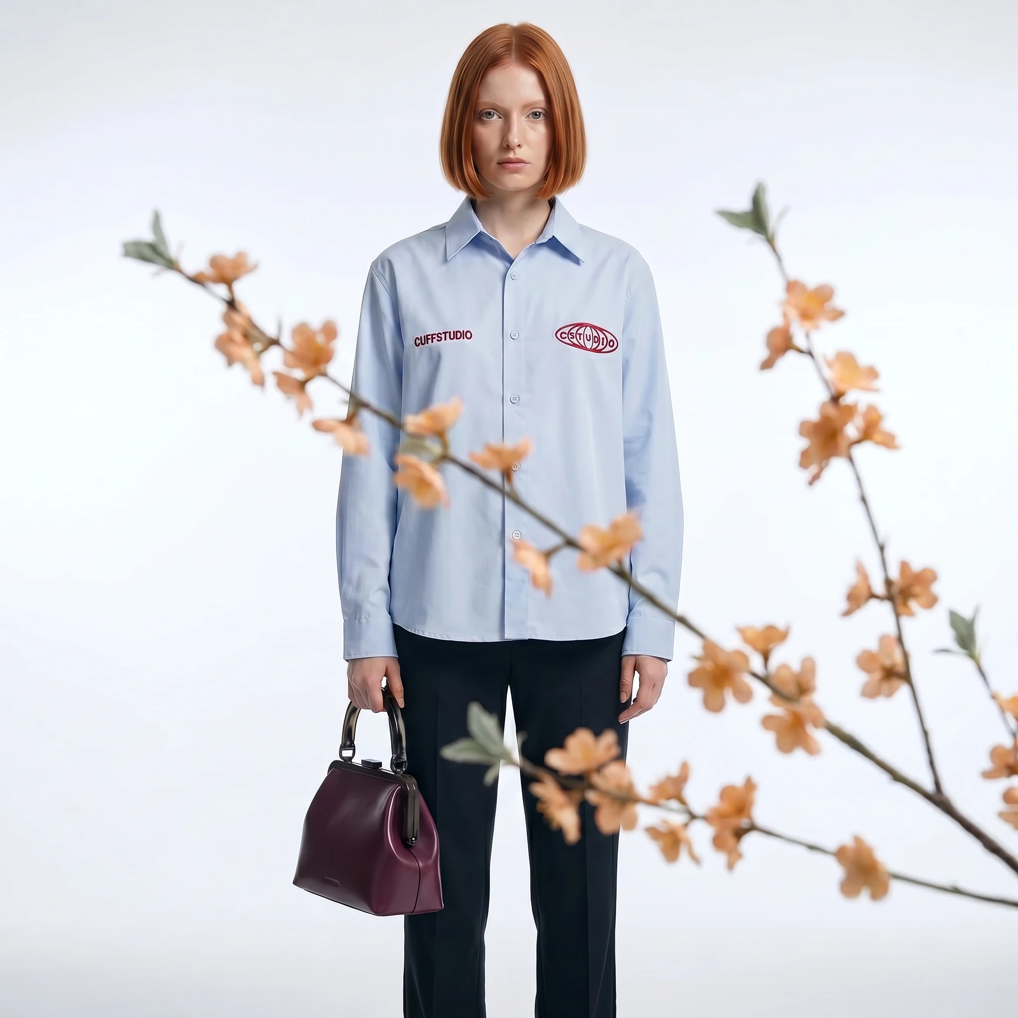 Fashion portrait with a blue shirt and handbag framed by blossom branches