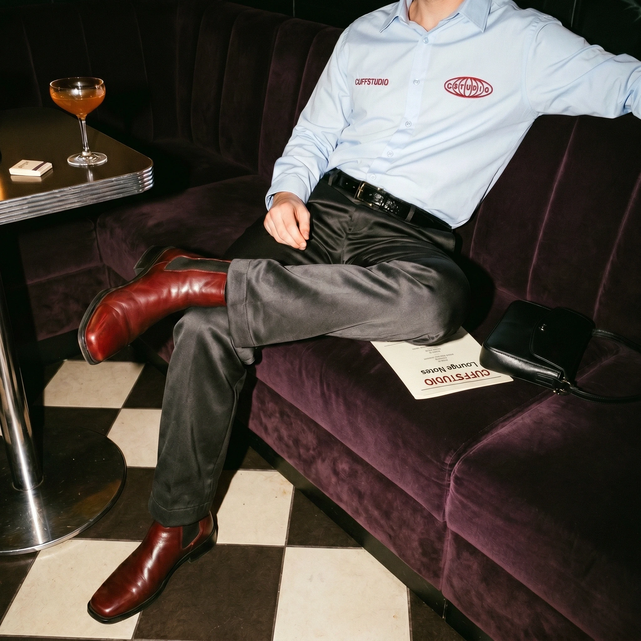 Fashion editorial featuring a blue shirt, grey trousers and red boots in a lounge