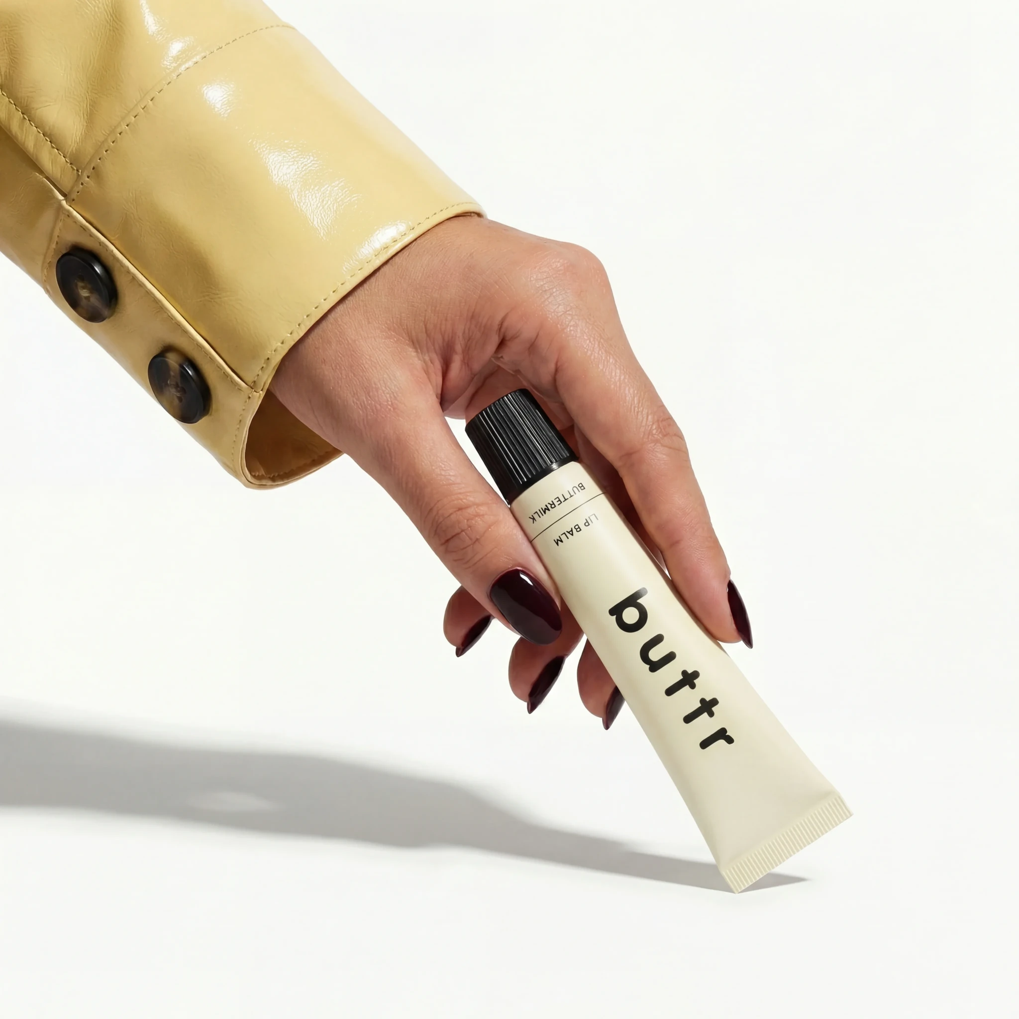 Hand holding a lip balm tube in a sunlit product close-up