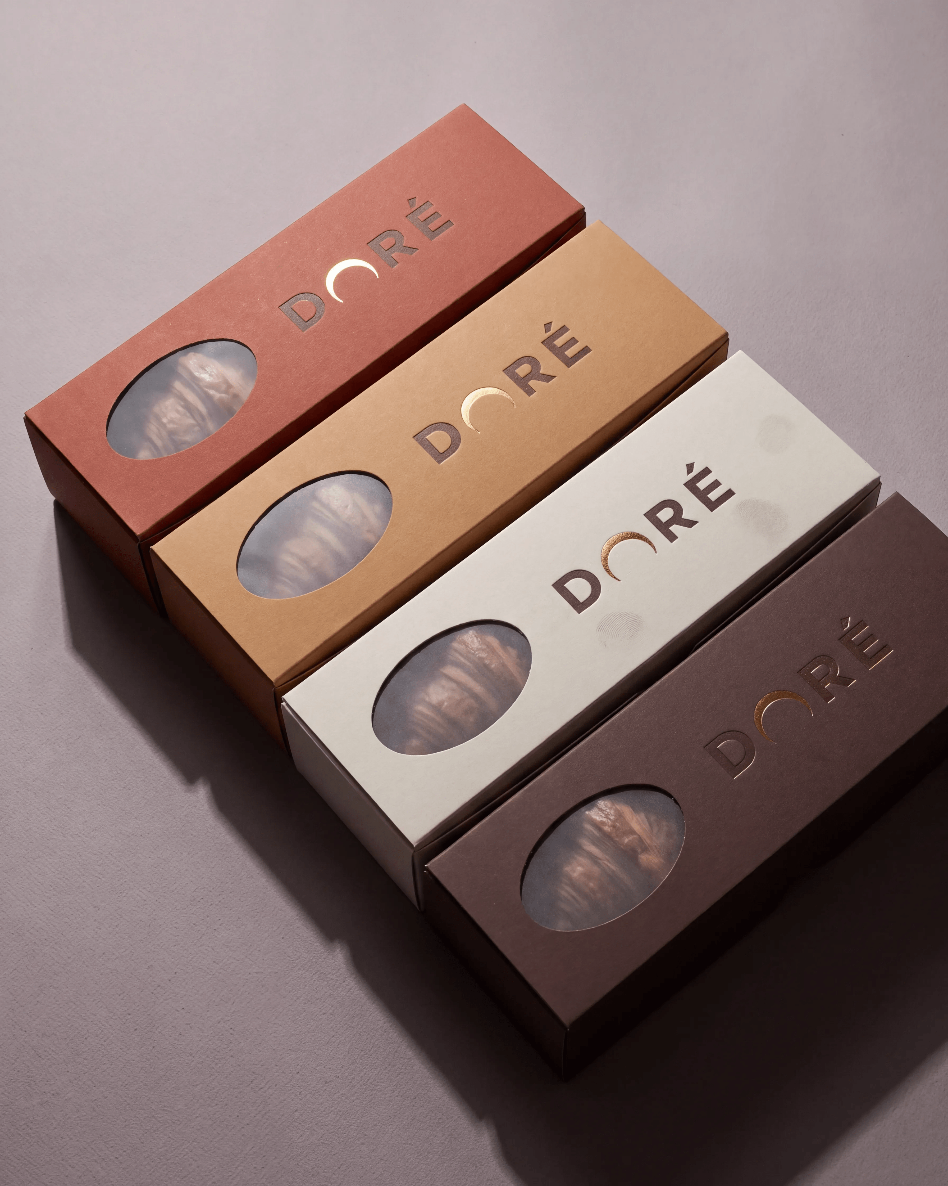 DORÉ: The Gift — Four boxes fanned out, gold foil wordmark, a window onto what is inside