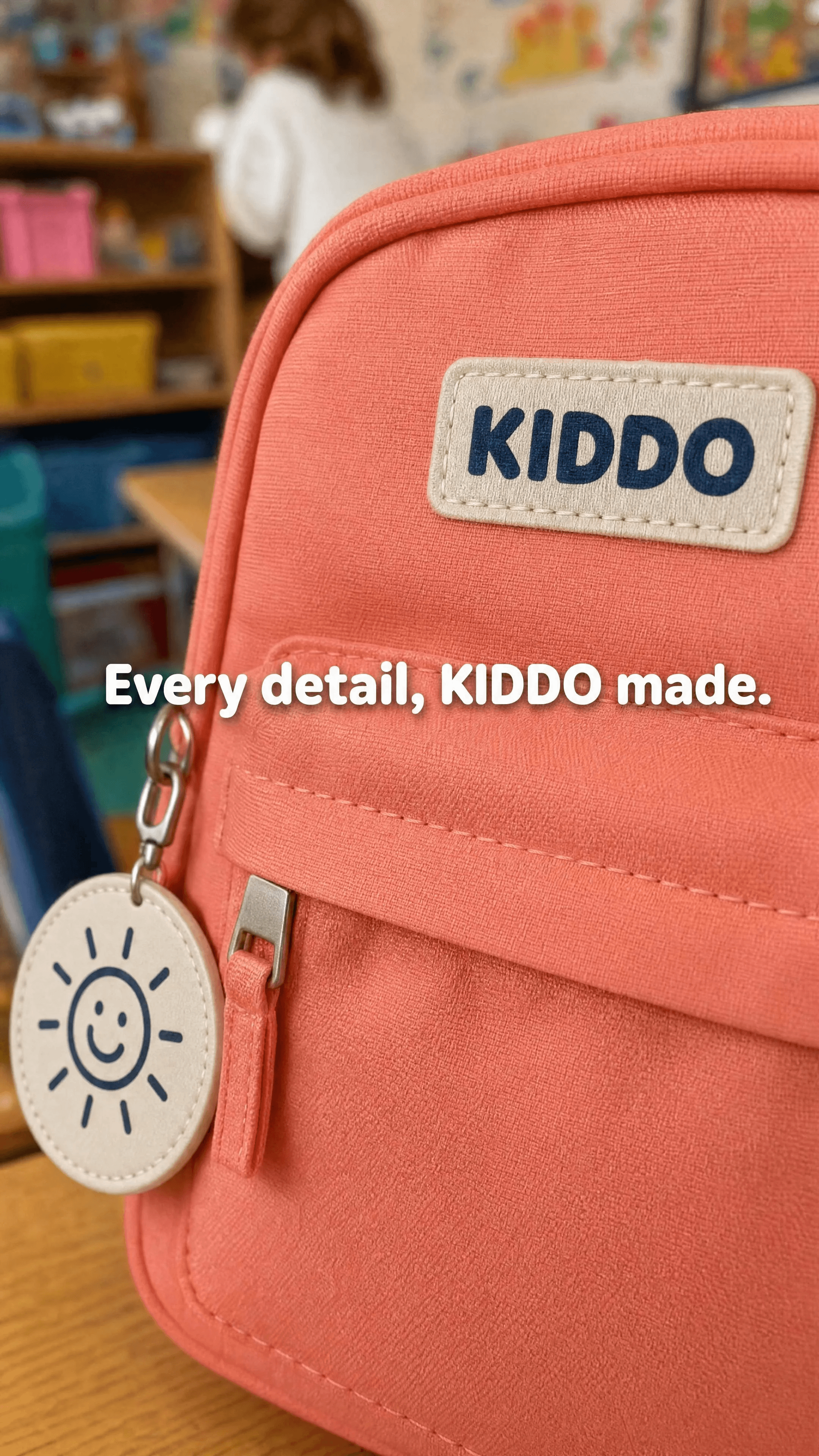 A close handheld view of the coral nylon, wordmark patch, zip, and sun-face charm.