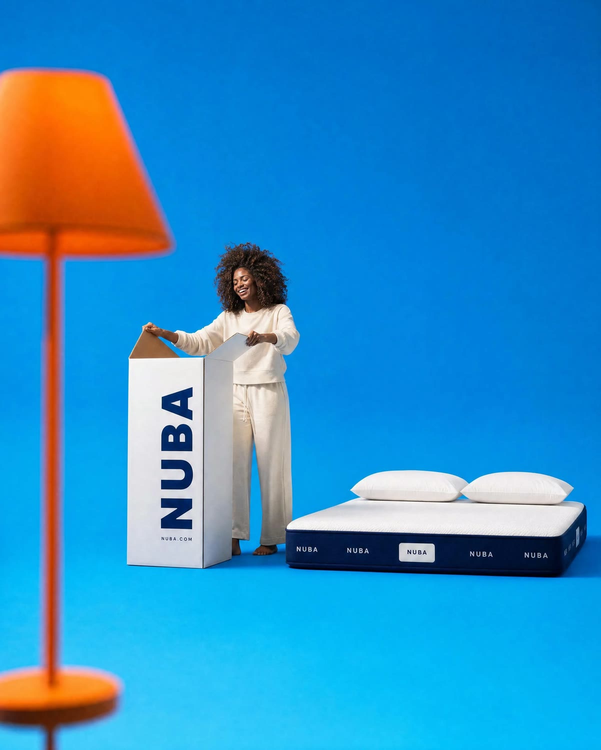 Model unboxing a NUBA mattress in a saturated blue studio