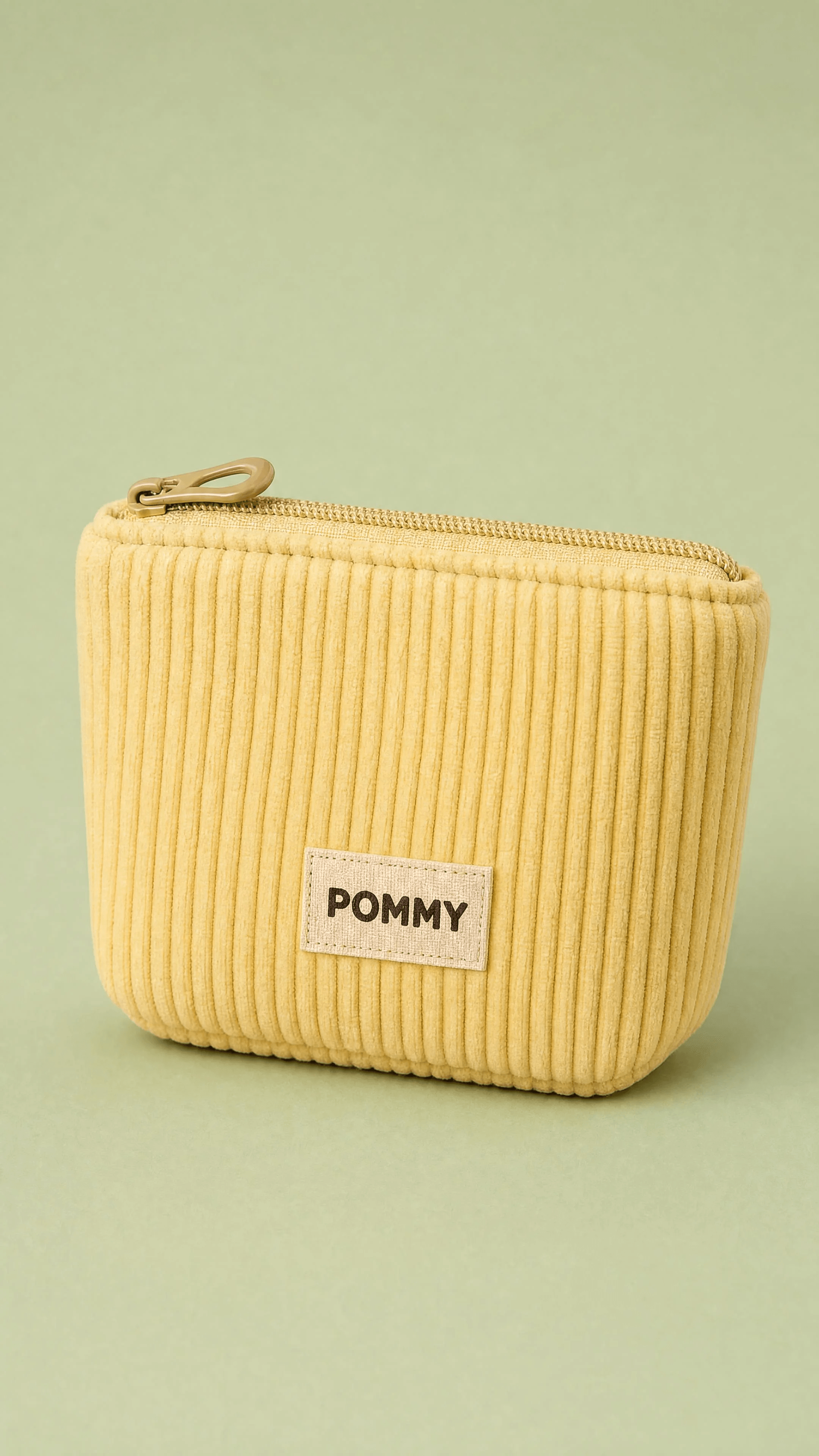 Close-up of a butter-yellow corduroy POMMY treat pouch and woven label